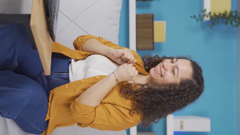 Vertical-video-of-Young-woman-looking-at-laptop-applauding.